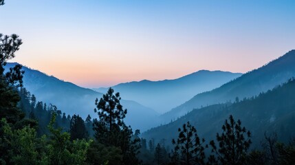 A serene mountain landscape at dawn with mist and soft colors.