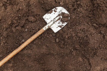 Brown dark soil ground texture background with copyspace and shovel top view