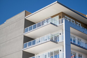 This is a corner view of a new apartment complex. The wall is grey, modern metal paneling. Each...
