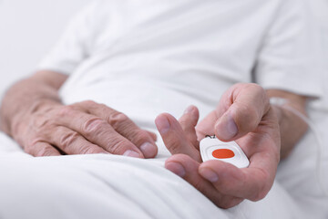 Senior man with emergency call button on bed in hospital, closeup