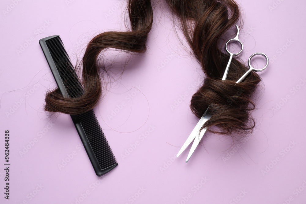 Wall mural Brown hair strand, comb and professional scissors on violet background, top view