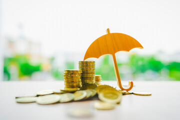 Model umbrella on a pile of money placed on the table is a figure with concepts of deposit...