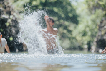 Energetic scene of young adults splashing water in a sunlit outdoor setting. Perfect for capturing the essence of summer fun and relaxation.