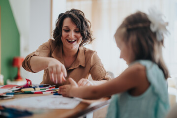 Fototapeta premium A joyful mom and her daughters engage in creative activities at home. They are surrounded by art supplies, fostering bonding and creativity in a cozy environment.