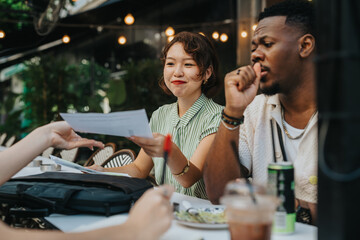 Friendly group of diverse colleagues discussing documents at an outdoor coffee meeting with casual ambience and lively conversation.