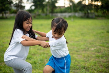 Two young girls playing soccer in a park.