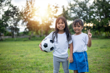 Two young girls are standing in a grassy field