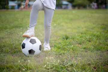 Obraz premium A young child is standing on a soccer ball in a grassy field