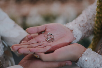 bride and groom is holding wedding rings. Bride with long nails and henna is holding wedding rings