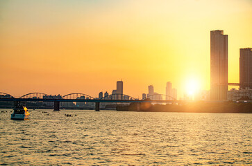 Obraz premium Sunsets behind the skyscrapers of yeouido and bridges across the Han River in Downtown Seoul, South Korea.