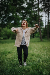 Obraz premium A joyful woman dancing in a lush green park, expressing freedom and happiness in a natural setting.