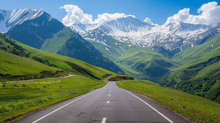 Naklejka premium Winding Road Through Mountain Pass with Green Hills and Snow Peaks