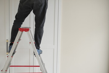 A person is standing safely on a ladder while working on a home improvement project © Towfiqu Barbhuiya 