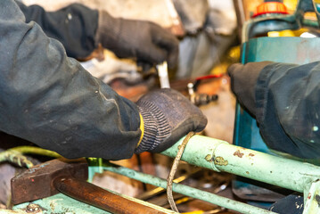 The gloved hand of a marine engineer grips a tool, set against the industrial backdrop of a ship’s engine room. The scene embodies the hands-on, mechanical work that keeps the vessel running smoothly.