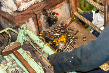 The gloved hand of a marine engineer grips a tool, set against the industrial backdrop of a ship’s engine room. The scene embodies the hands-on, mechanical work that keeps the vessel running smoothly.