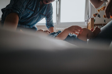Naklejka premium Heartwarming scene of parents lovingly interacting with their baby in a cozy home setting, highlighting family bonds and tender care.