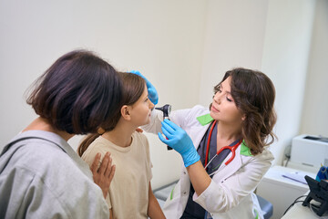 Obraz premium Family doctor uses a special instrument to examine