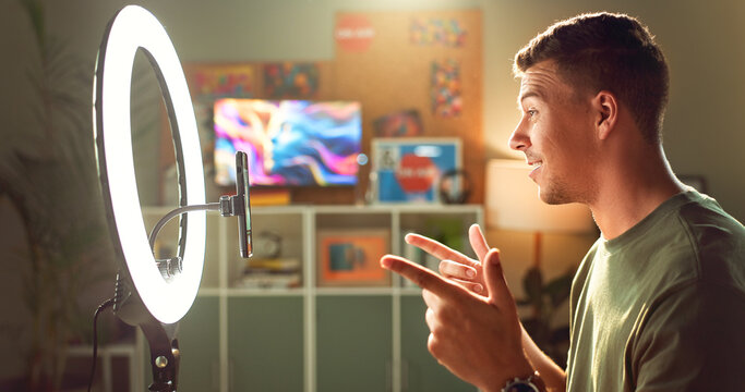 Influencer, ring light and smile at mobile for streaming, follower interaction and content creation. Man, gamer and phone in home for subscriber engagement, introduction and connectivity in profile