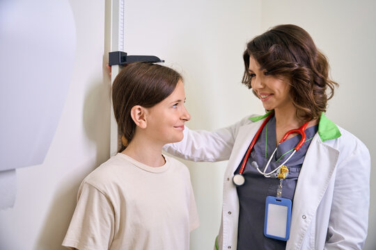 Family doctor measures the height of a teenage patient