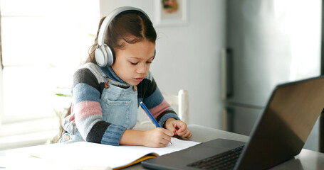 Home, girl and homework with laptop for education, elearning and connection for online class. Child, studying and cognitive development with writing for learner, knowledge and headphones in kitchen