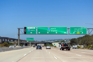 Overhead freeway signs on Interstate 5 North towards Los Angeles, with separate lanes for HOV and local bypass routes. Light traffic on the road. Selective focus