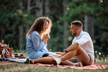 Young woman crying out of joy while having romantic picnic with her boyfriend in nature.