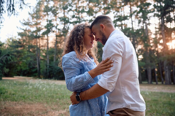 Fototapeta premium Young loving couple standing face to face in nature at sunset.