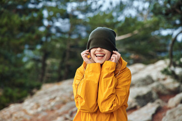 Happy woman in stylish yellow raincoat enjoying a rainy day with hands to her face Fashionable Rainy Day Beauty Smile Travel Concept