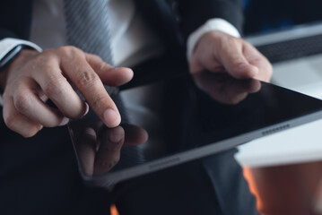 Businessman standing at table using digital tablet at modern office, close up. Business man working on table computer devices, surfing the internet at workplace