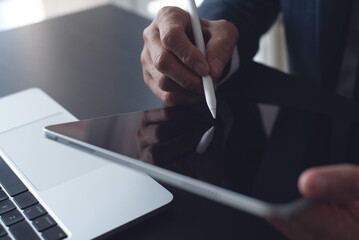 Close up, businessman using stylus pen signing e-document on digital tablet at office, E-signing, electronic signature concept. Business man online working on computer devices on office desk