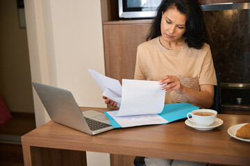 Female works with documents over breakfast in her room
