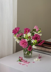 A bouquet of garden flowers, a laptop, notebooks on a white table