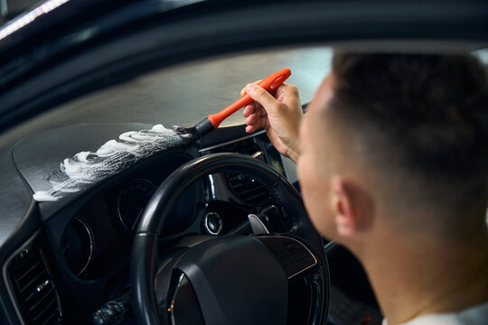 Man cleans a panel in a car
