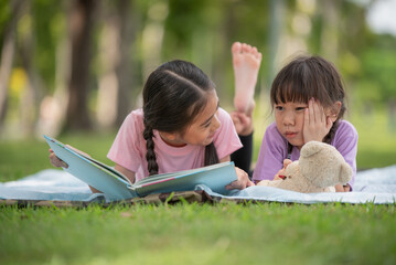 Happy Asian family children elder sister and younger sister reading a book together