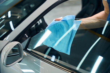 Male rubs car windows with a soft napkin