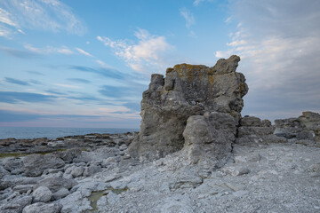 Large solitary rock standing tall against sea horizon