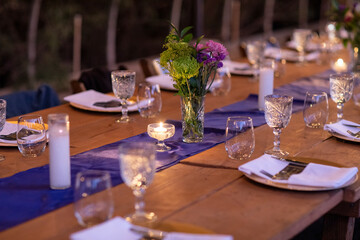 Communal table set for dinner service by candle light