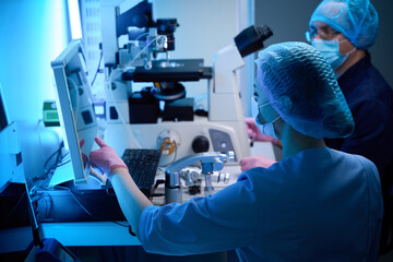 Adult specialists adjusting settings on lab machinery