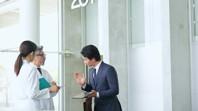 白衣の技術者に説明するビジネスマン