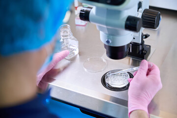Caucasian doctor handling sample under microscope in laboratory setting
