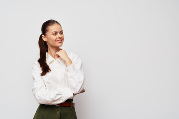 Smiling young woman in a white shirt and green skirt against a light gray background Confident pose with thoughtful expression Ideal for business concepts and lifestyle images