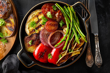 grilled vegetables - eggplant, pepper, onion, tomato and beans on black background top view