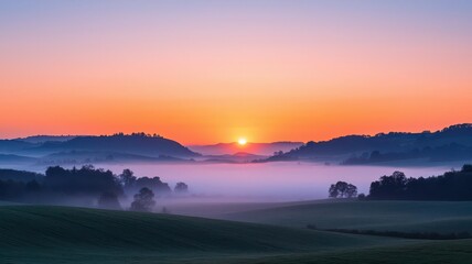 Obraz premium A serene sunrise over misty hills, capturing the beauty of nature's tranquility and the beginning of a new day.