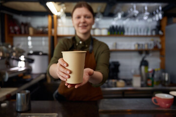 Closeup view on takeaway paper cup of coffee in barista hands