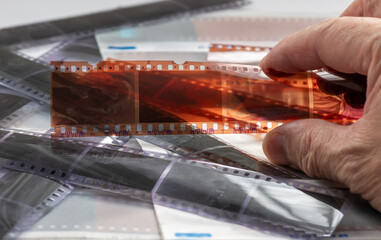 A person holding a strip of colour film negatives to examine the processing results.
