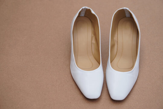 Pair iof white shoes on brown background. Concept, fashion, formal and polite footwears for office workers or nurses to wear shoes in office or hospital to match with white uniform. Footwears.     