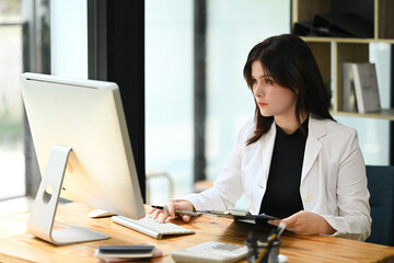 Focused businesswoman looking at computer, working at desk office