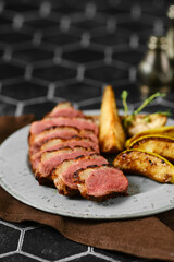 Seared duck breast with wedges of roasted slices of apple and pear on a plate