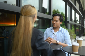 Fototapeta premium Two young businesspeople having a conversation at an outdoor cafe