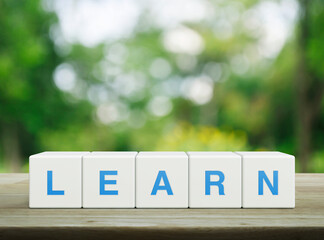 Learn letter on white block cubes on wooden table over blur green tree in park, Business, education and learning concept